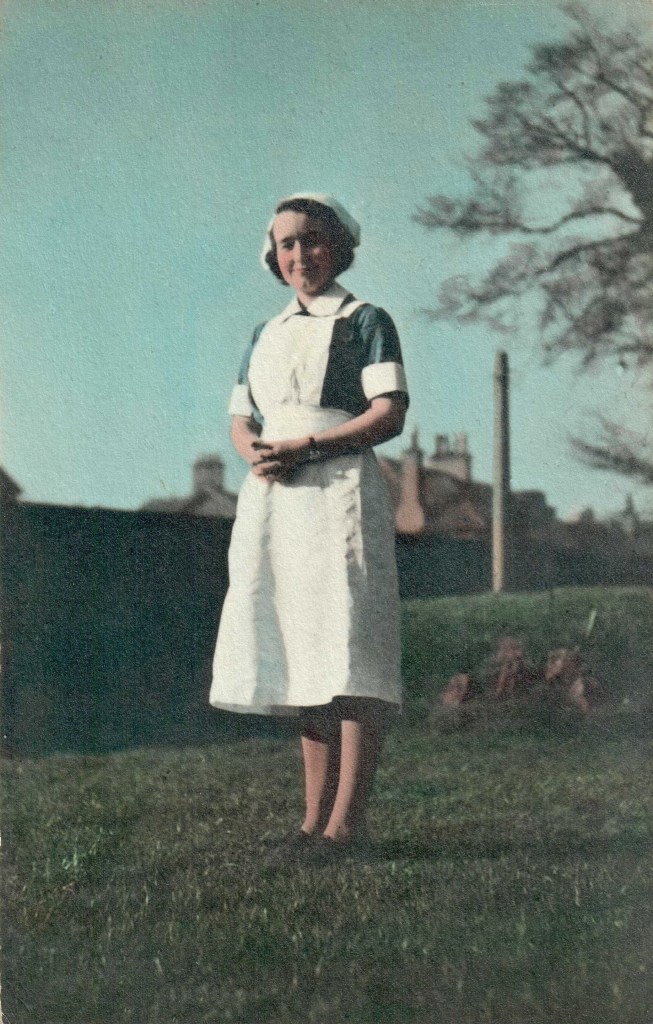 Woman in nurse's uniform standing outside next to a tree